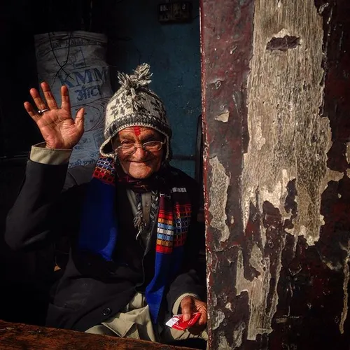 An elderly Nepalese man reacts to the camera while he sit