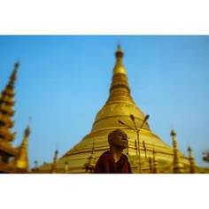 A Buddhist monk passes in front of the main spire of Shwe