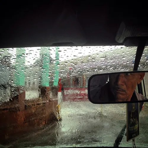 A taxi driver is reflected in a rear view mirror inside h