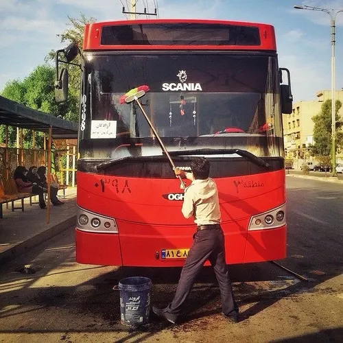 A driver cleans his bus down on street. Ahwaz, Khuzestan,