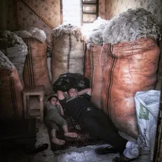 A man resting in his wool shop with his little son in Tab