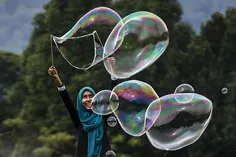 دختر مسلمان در حال بازی با حباب در پارکی در کوالالامپور م