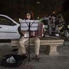 A woman plays the accordions at the side of a street. #Te