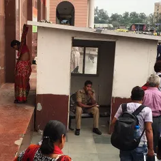An Indian woman adjusts her sari behind a police constabl