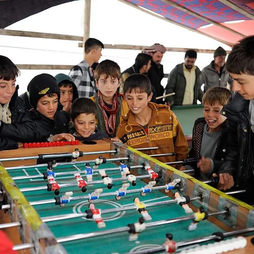 A group of displaced Yazidi boys play foosball in a tent 