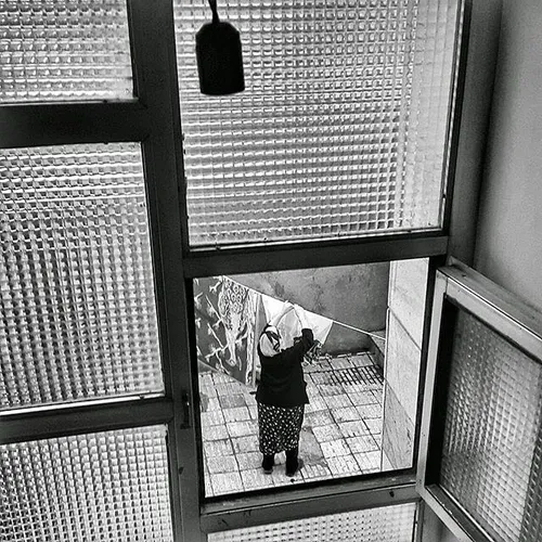 A woman hanging some clothes up to dry at the backyard. A