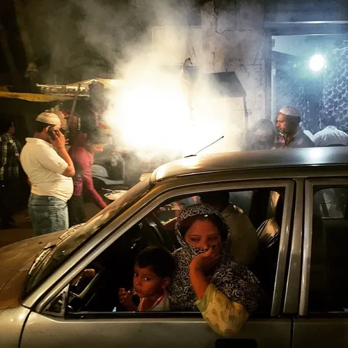 An Indian woman covers her face from the smoke caused by 