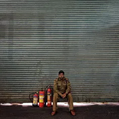 An Indian security personnel looks on as he sits inside a