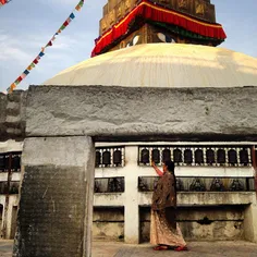 A Nepalese woman spins prayer wheel in Charumati Stupa in