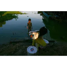 A Vietnamese Cambodian little girl carry water from Tonle