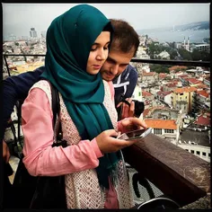 A young couple reviews the selfies they took at the top o