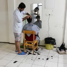 A student cutting his friend’s hair in a university dormi