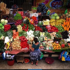 A woman organizes fruits and vegetables at a food stand i