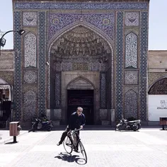A man rides on his bike in front of Vakil Mosque which is