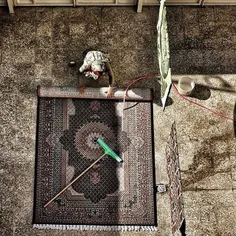A woman scrubs a carpet at the yard before Norouz. Irania