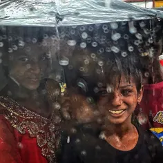 Indian children takes shelter under an umbrella during he