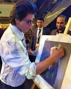 شاهرخ خان درحال امضای عکس خودش.