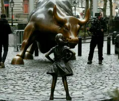 قرار گرفتن یه مجسمه دختر در مقابل مجمسه یک گاو در وال است