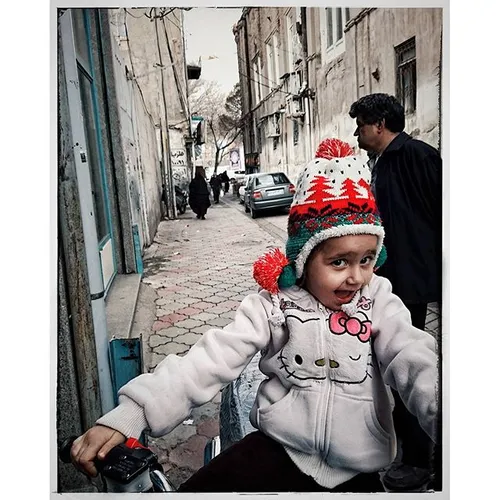 A young girl playing with her father's motorbike, near Ta