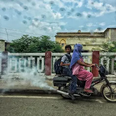A young Indian boy reacts to the smoke emitted by a moped
