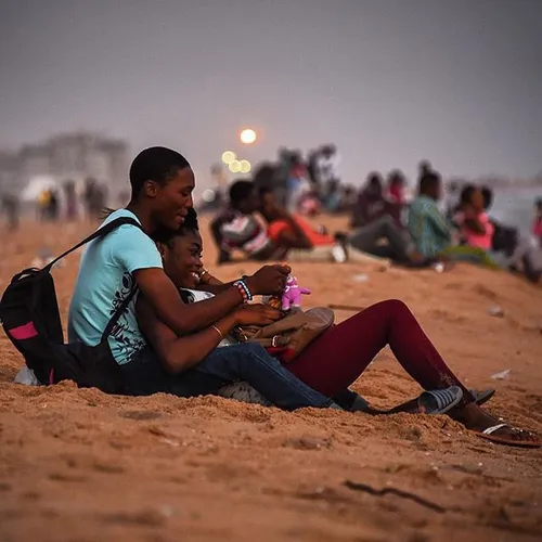 A couple watches the sunset on a beach in Cotonou, Benin.