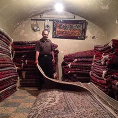 Shopkeeper shows customers handmade carpets. #Qazvin, #Ir