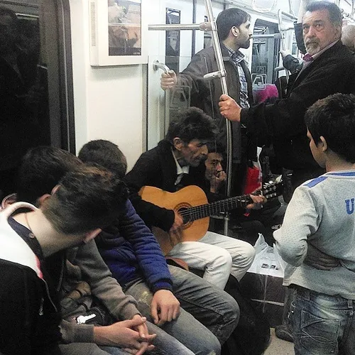 A musician playing the guitar in a subway train. Tehran, 