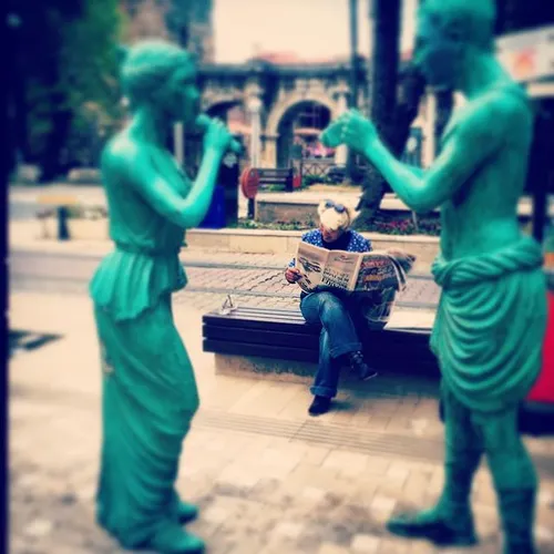 A Turkish man reads a newspaper between two statues in an