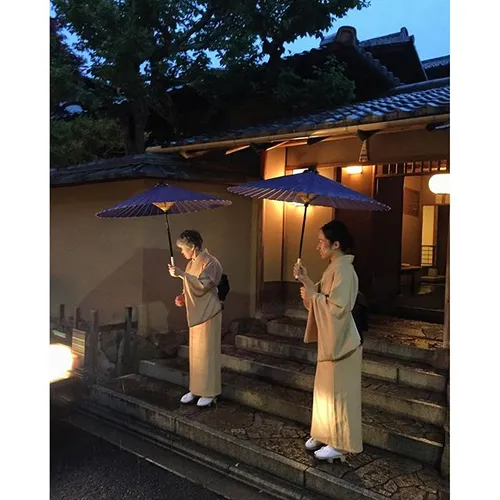 Women in kimono waves goodbye to guest in front of a rest